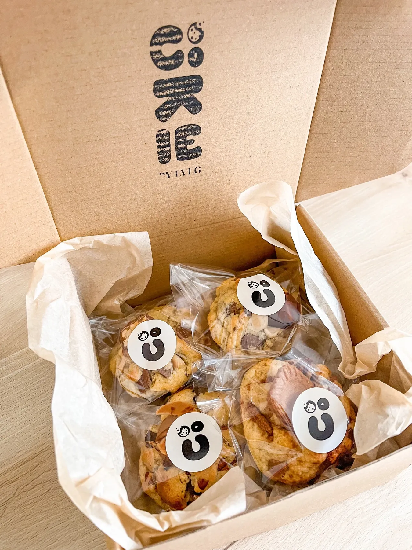 La box Cookie By LVEG ouverte, avec le logo sur le couvercle et les cookies dans leurs sachets